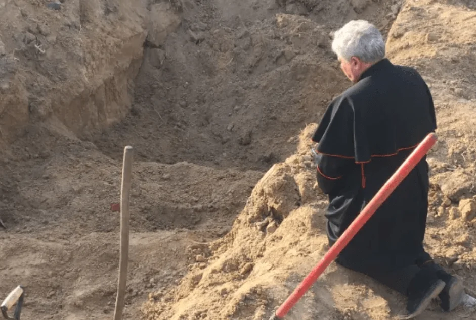 Un envoyé du pape prie dans une fosse commune en Ukraine